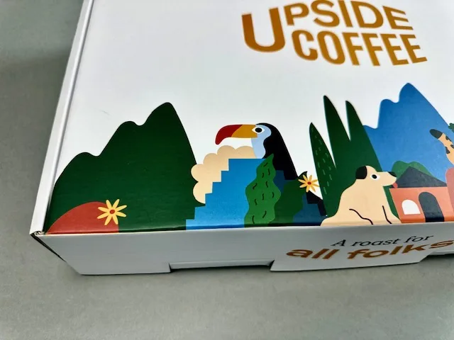 Pudełko marki kawowej Upside Coffee z ilustracją tukana i g&oacute;r &ndash; realizacja AQRAT